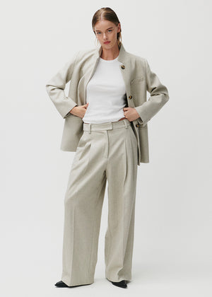 Woman wearing a beige blazer and wide-leg pants on a white background