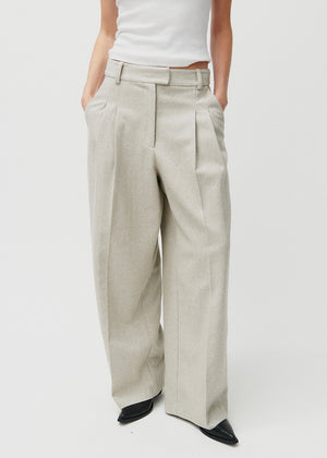 Person wearing beige wide-leg pants and a white top on a light gray background