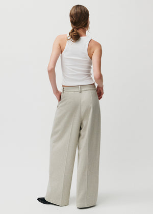 Person wearing a white sleeveless top and beige wide-leg pants on a plain background