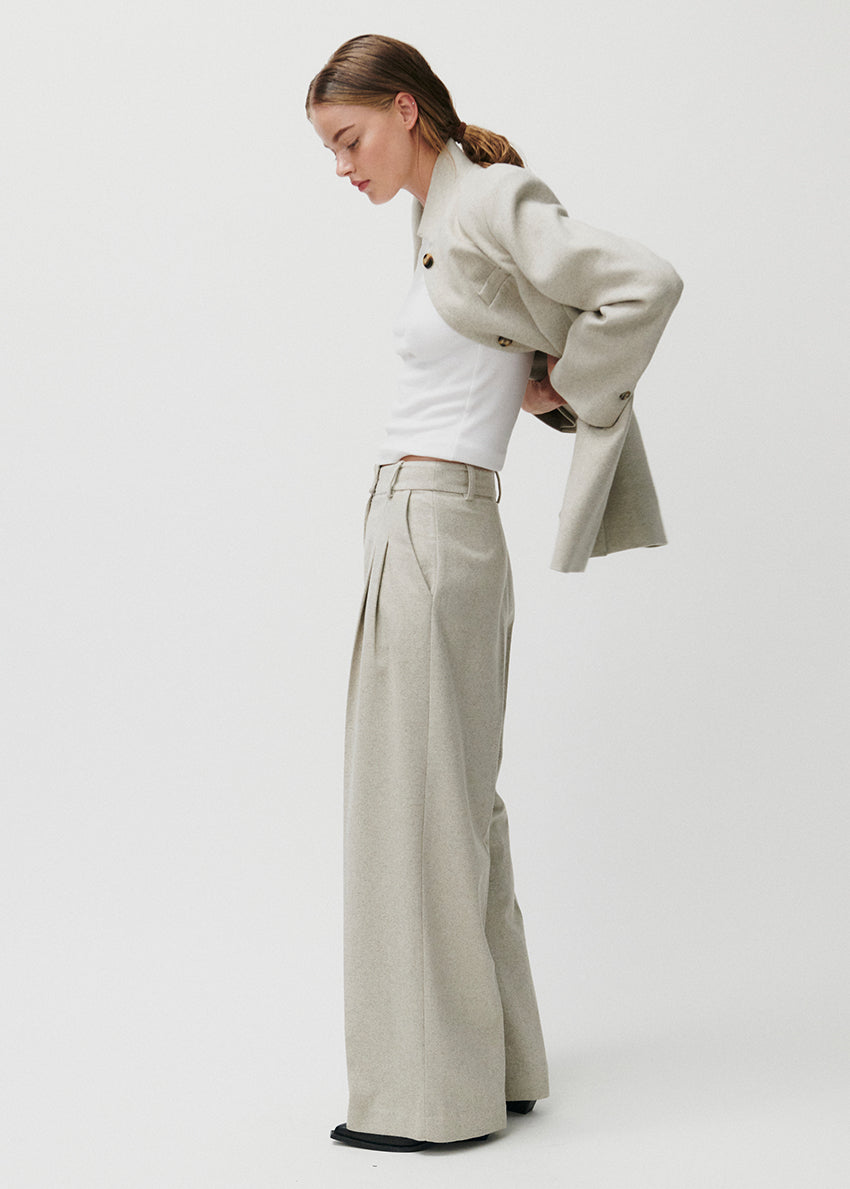Person wearing beige wide-leg pants and a white top on a light gray background