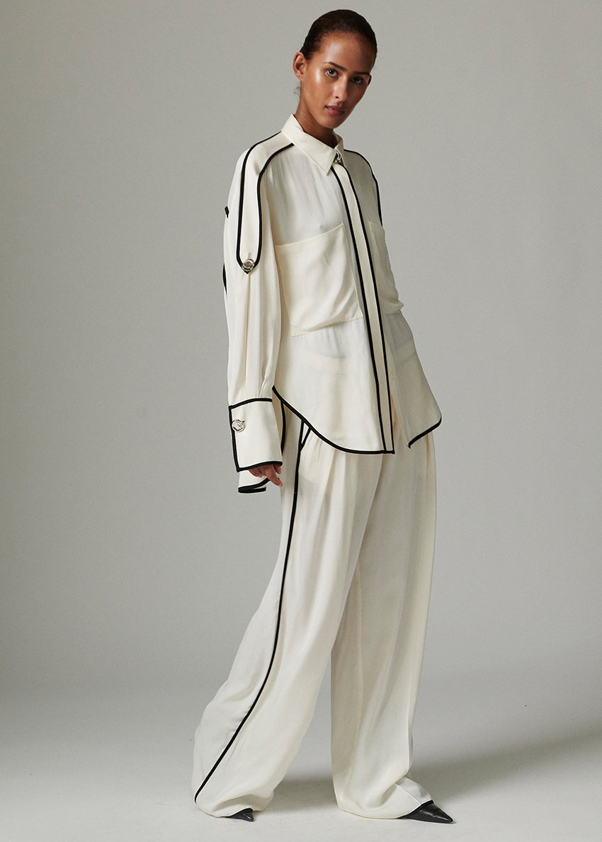 This fluid, button-up top features contrast piping, epaulets at the shoulders, and a dipped hem. There are two pockets at the chest.