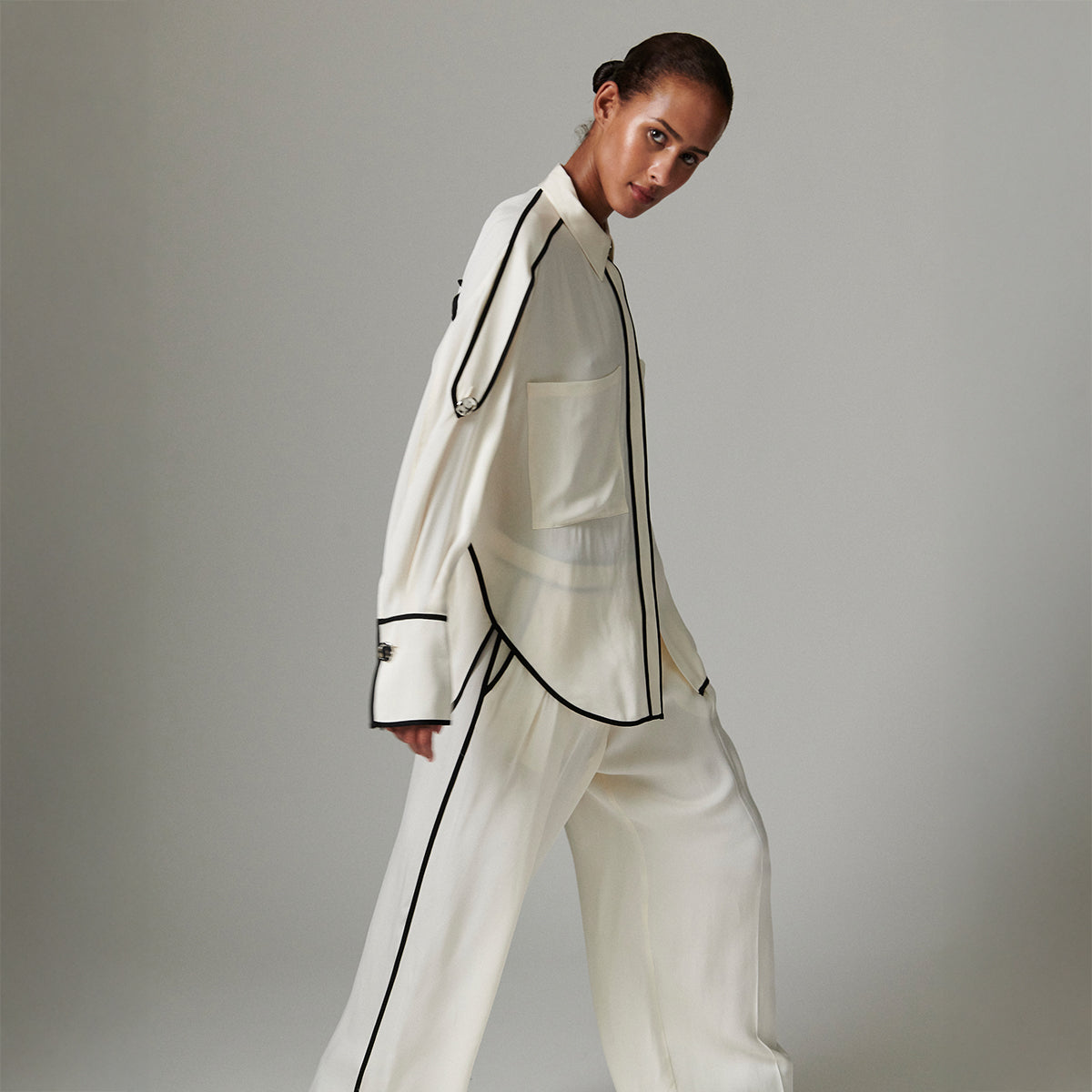 Person wearing a white outfit with black accents on a gray background