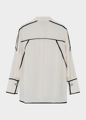 This fluid, button-up top features contrast piping, epaulets at the shoulders, and a dipped hem. There are two pockets at the chest.