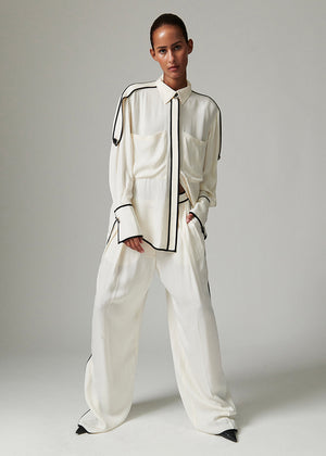 Model wearing a white outfit with black accents against a plain background