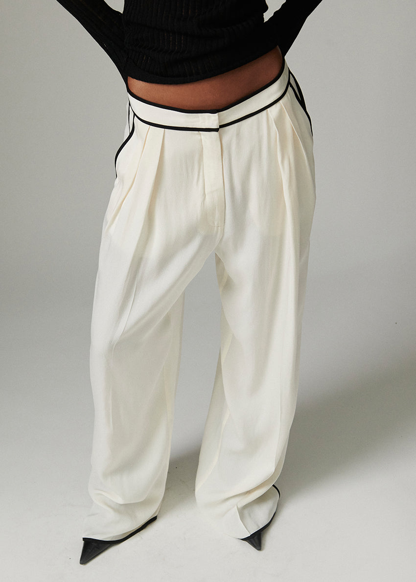 White wide-leg pants with black trim worn by a person on a plain background