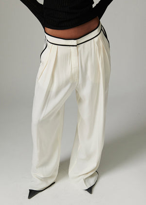 White wide-leg pants with black trim worn by a person on a plain background