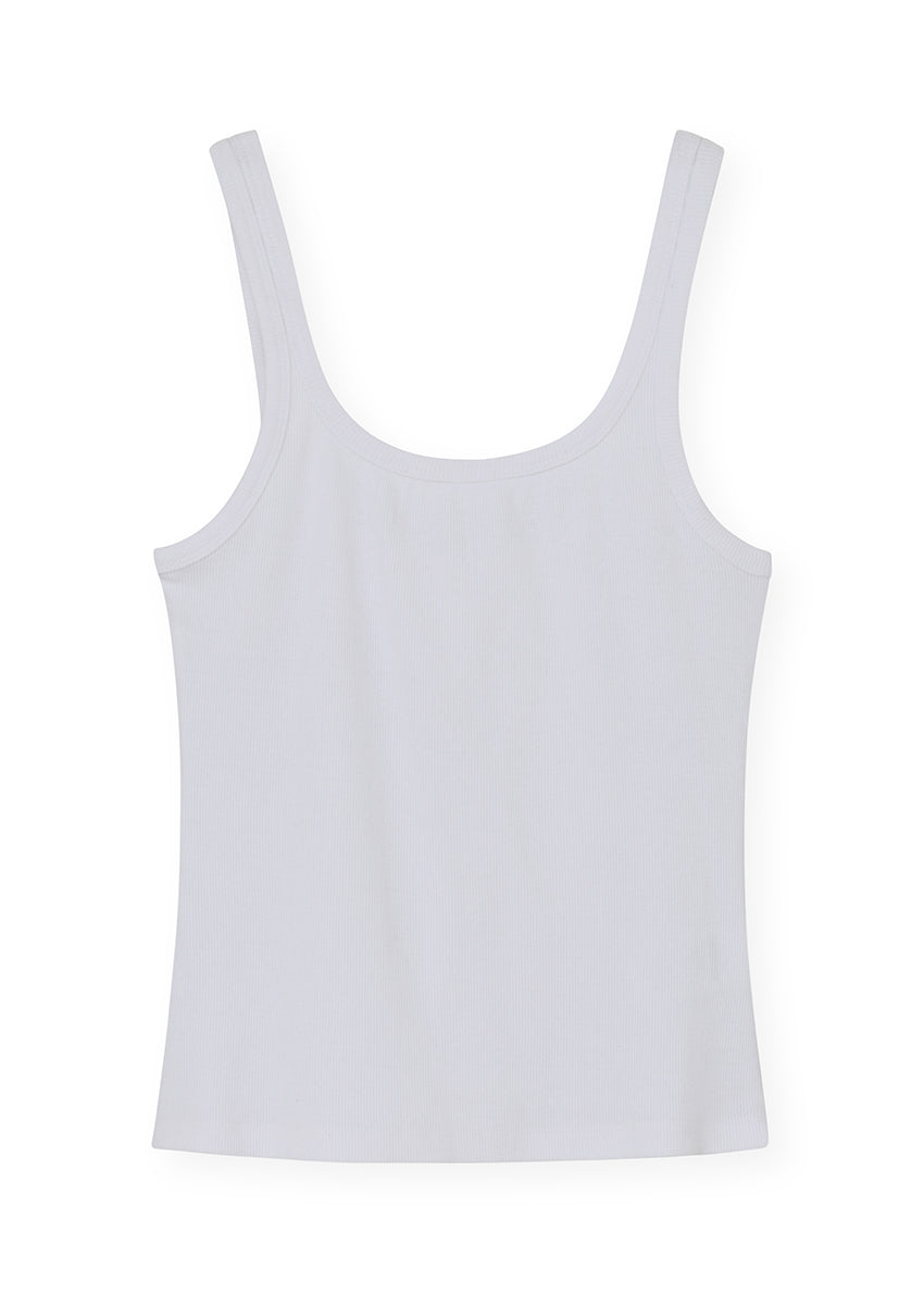 Person wearing a white tank top and black pants with a neutral background