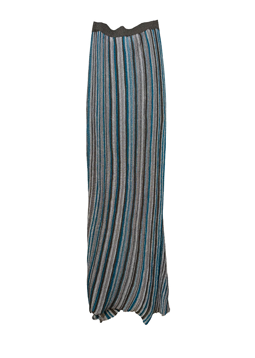 Person wearing a long, striped dress with a matching jacket and holding a patterned bag on a white background.