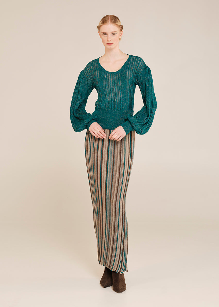 Woman wearing a teal sweater and striped pants on a beige background