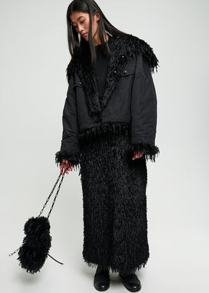 Person wearing a black outfit with fringe details on a white background