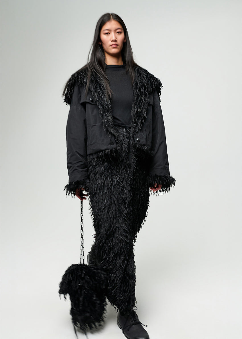 Person wearing a black feathered outfit on a plain background