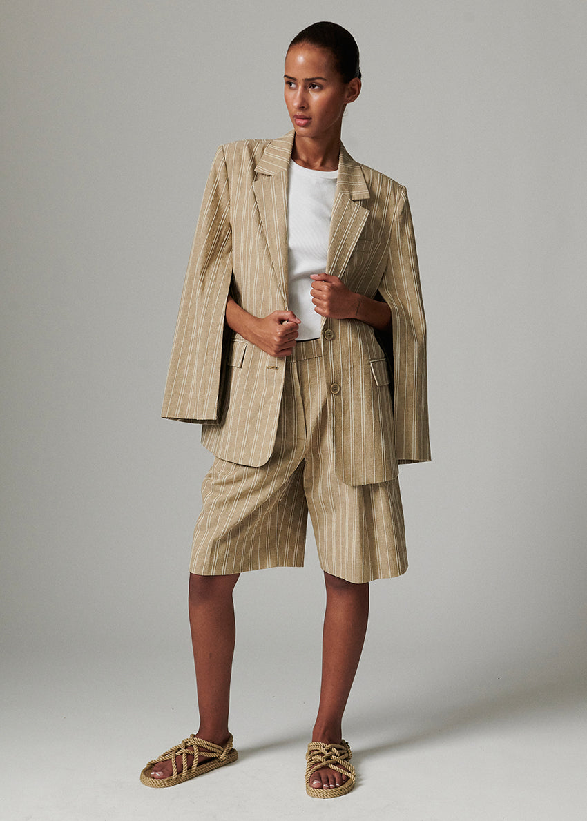 Woman wearing a beige striped suit against a plain background