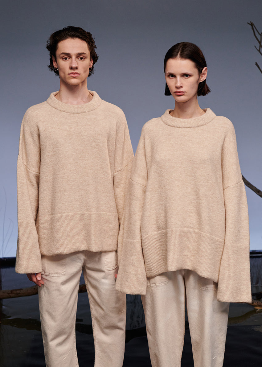 Two models wearing matching beige outfits standing against a neutral background.