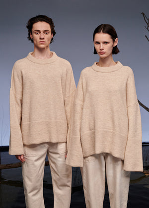 Two models wearing matching beige outfits standing against a neutral background.