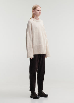 Person wearing a beige sweater and black pants on a white background