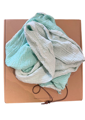 Stack of light-colored fabric on a cardboard box with a brown strap.