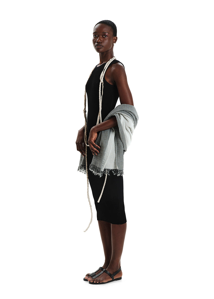 Model wearing a black dress with a white shawl, standing against a white background