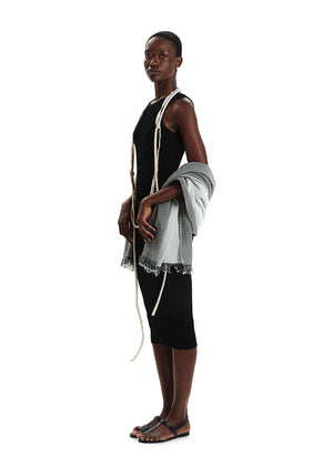 Model wearing a black dress with a white shawl, standing against a white background