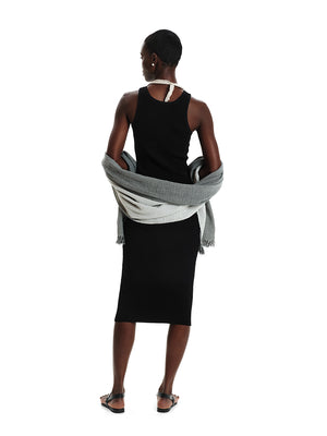 Person wearing a black sleeveless top and skirt with a gray scarf, standing against a white background