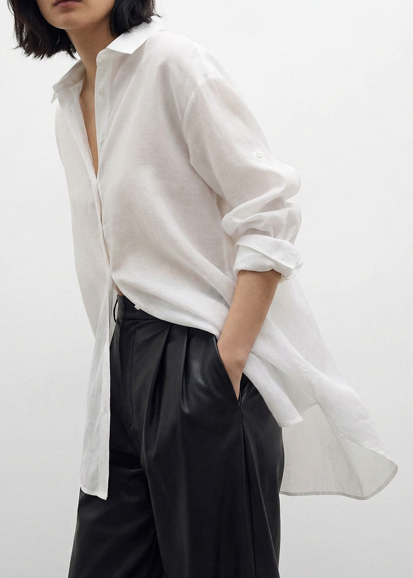 Person wearing a white shirt and black pants on a plain background