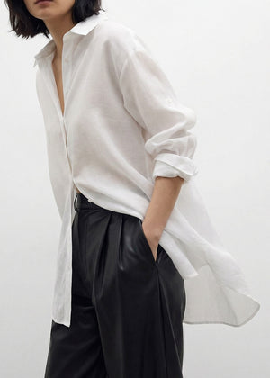 Person wearing a white shirt and black pants on a plain background