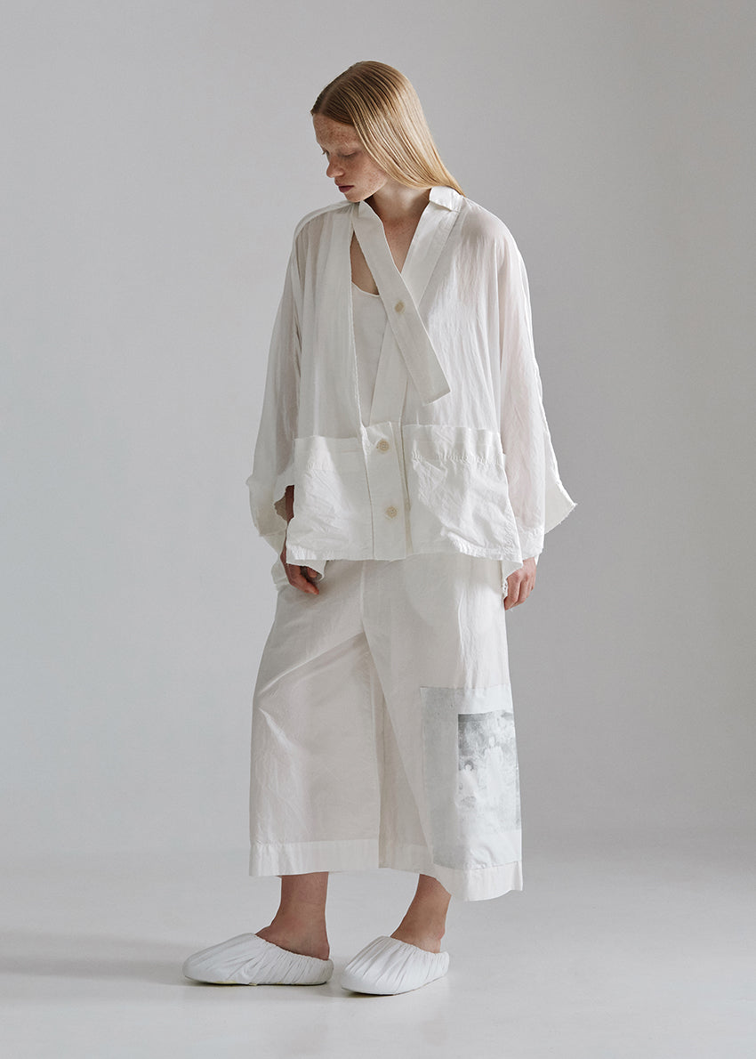 Person wearing a white outfit with a plain background