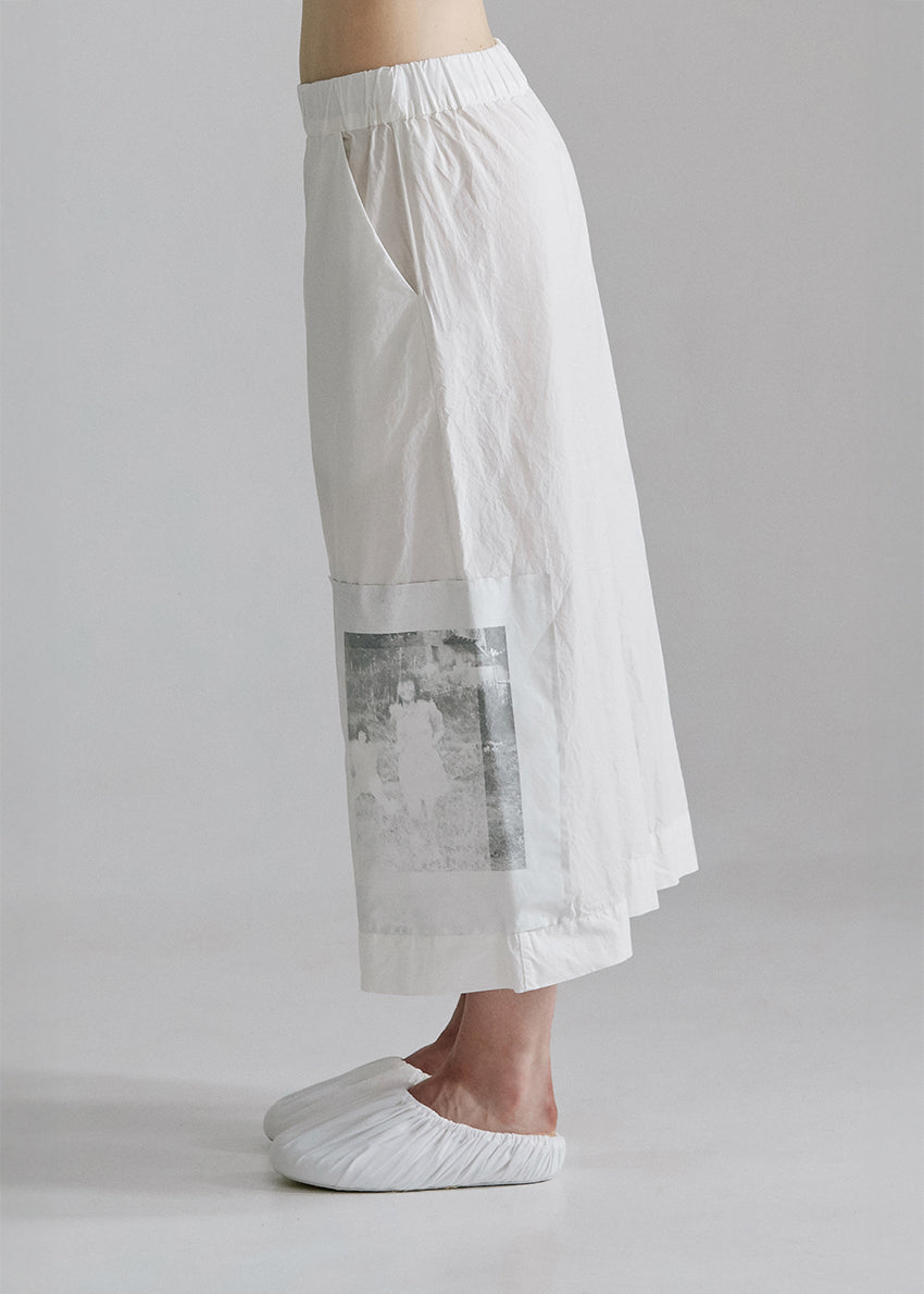 Person wearing a white outfit with a plain background