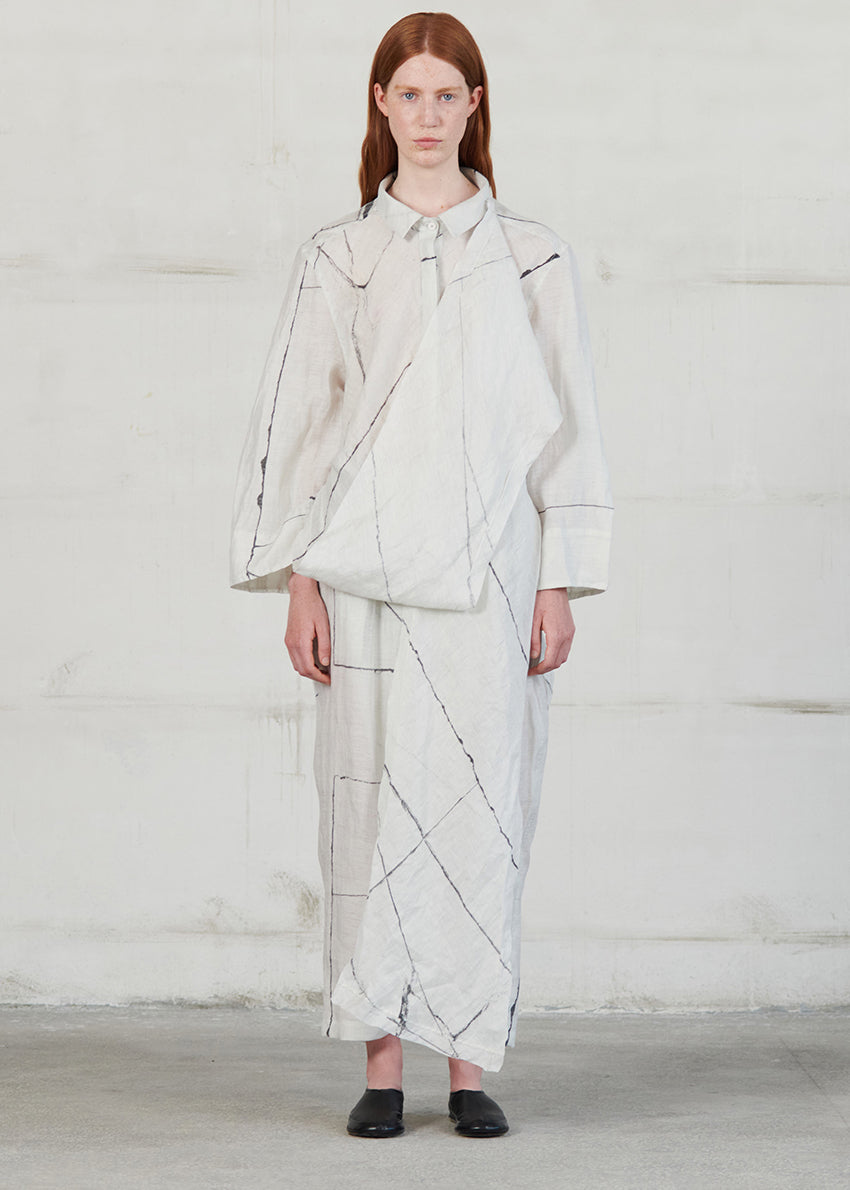 Person wearing a light-colored outfit with geometric patterns against a white background