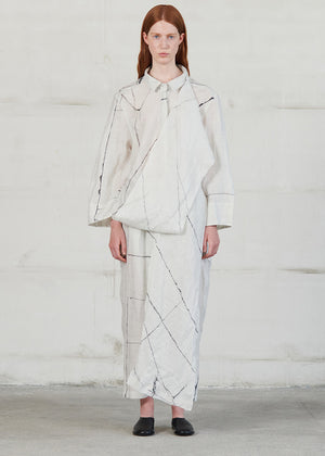 Person wearing a light-colored outfit with geometric patterns against a white background