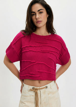 Woman wearing a bright pink ruffled top against a white background