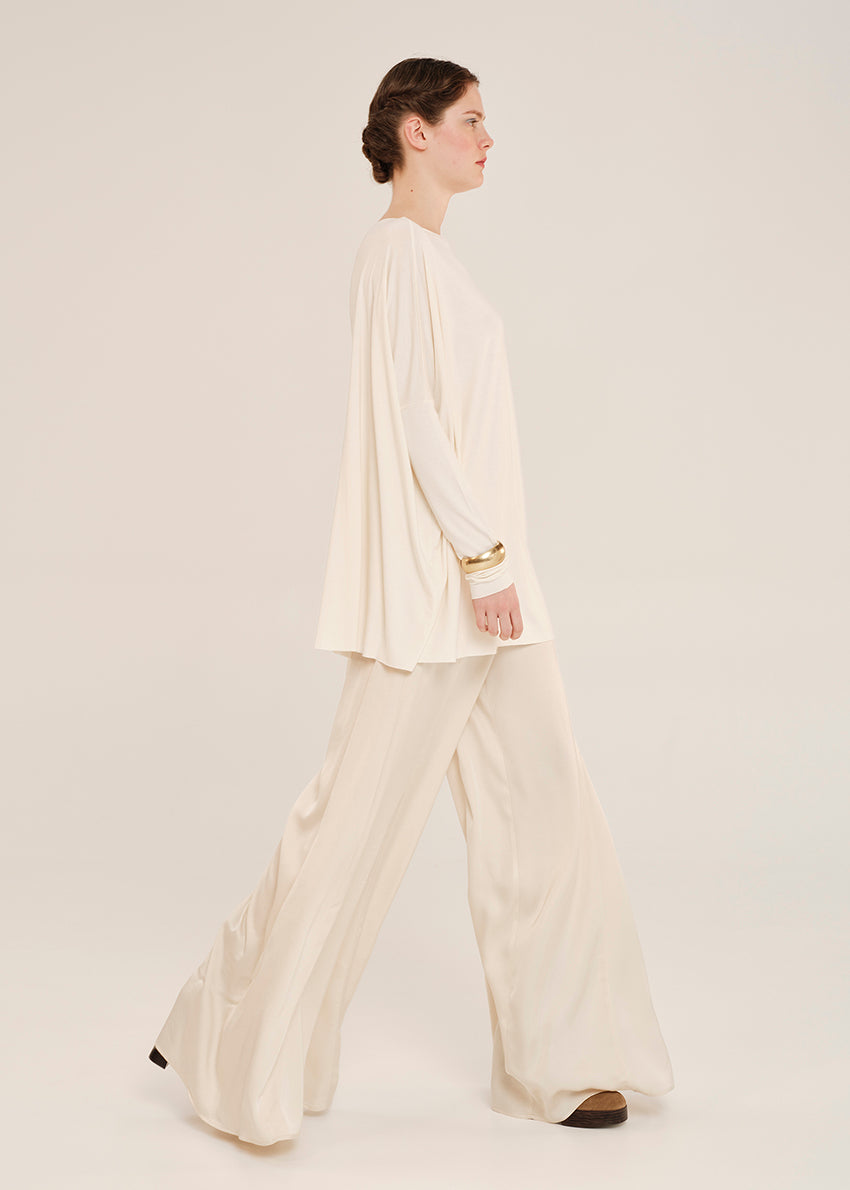 Woman wearing a cream-colored outfit on a plain background