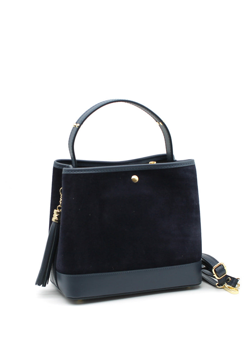 A midnight blue suede and leather handbag with a circular handle, fringe accents, and a crossbody strap.