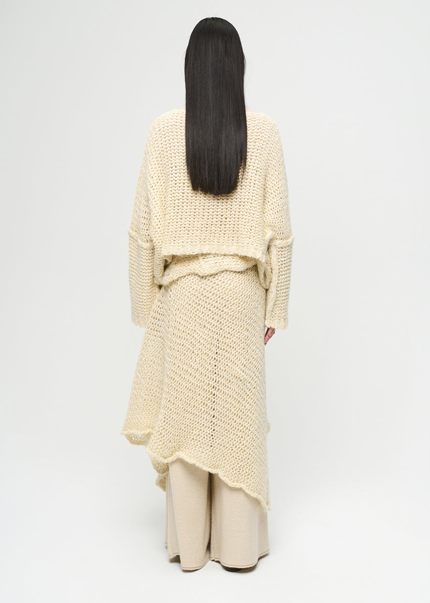 Person wearing a cream-colored knit outfit on a white background