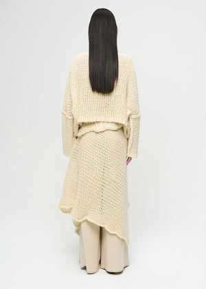 Person wearing a cream-colored knit outfit on a white background