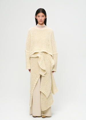 Woman wearing a cream-colored knit outfit on a white background