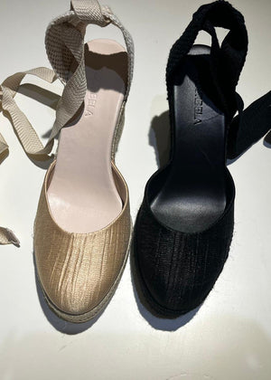 Pair of gold and black open-toe shoes on a white background