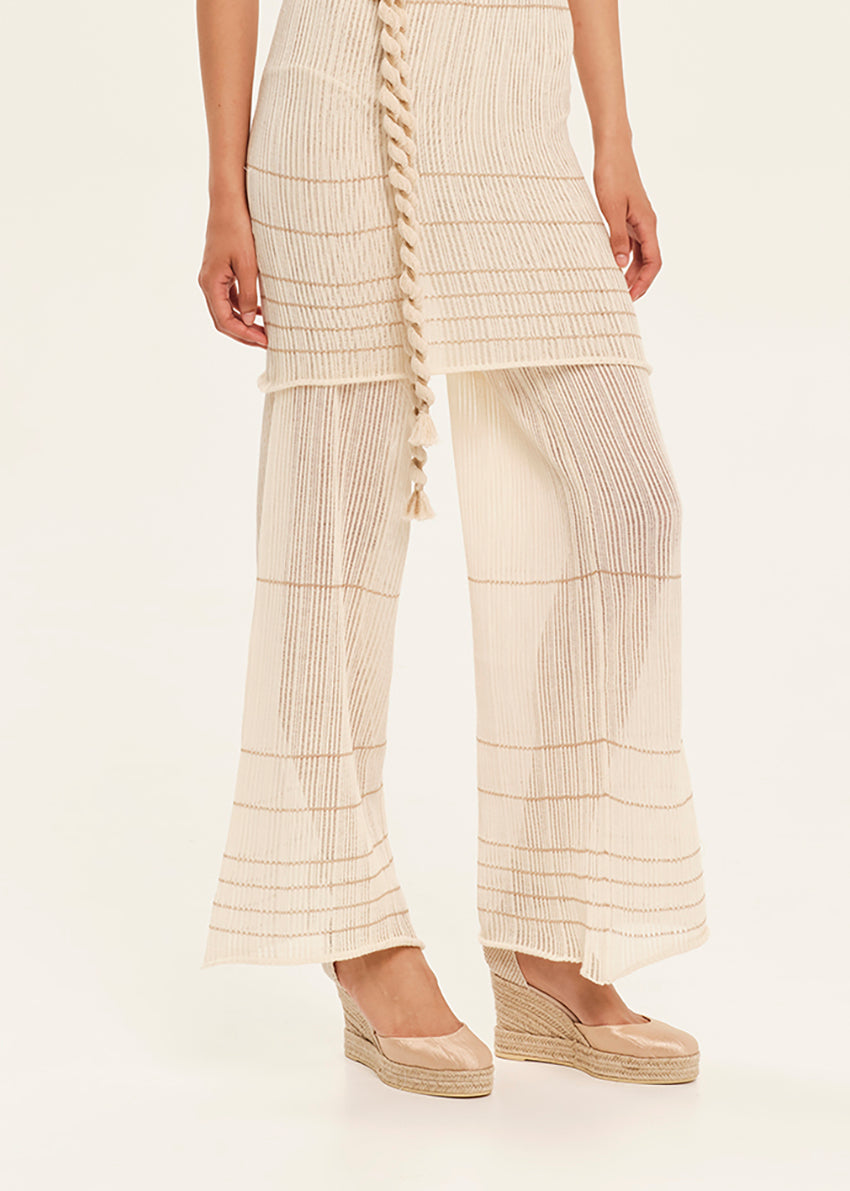 Person wearing a beige pleated outfit with a white background