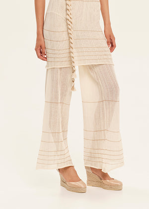 Person wearing a beige pleated outfit with a white background