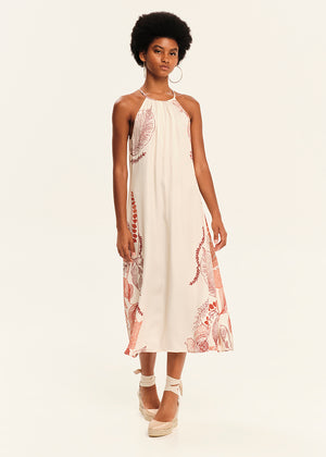 Woman wearing a white dress with floral embroidery on a plain background