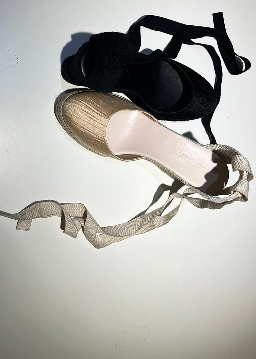 Pair of high-heeled shoes with ribbons on a light background