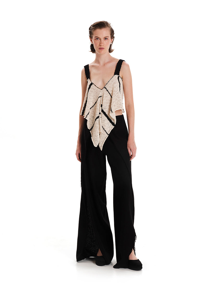 Woman wearing a black and beige sleeveless top with wide-leg pants on a white background