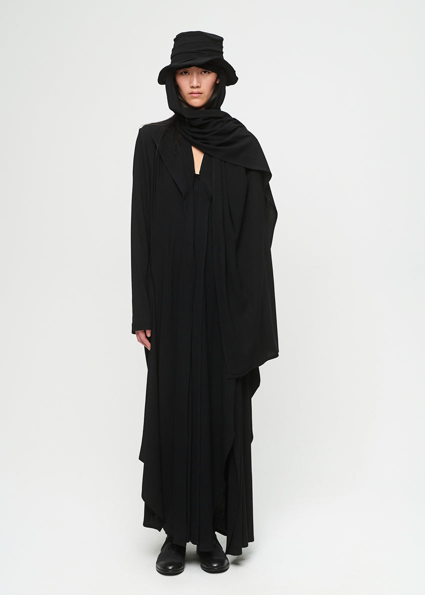 Person wearing a long black dress with a hood on a white background