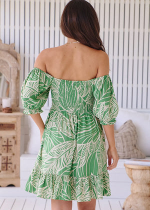 This Jaase Evergreen Louise Mini Dress features playful off-the-shoulder sleeves, a shirred body, and a short length. Perfect for a casual day look with sneakers or dressing up for a night out. Its all-over tropical-inspired green print is sure to add a touch of botanical beauty.