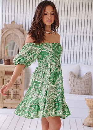 This Jaase Evergreen Louise Mini Dress features playful off-the-shoulder sleeves, a shirred body, and a short length. Perfect for a casual day look with sneakers or dressing up for a night out. Its all-over tropical-inspired green print is sure to add a touch of botanical beauty.