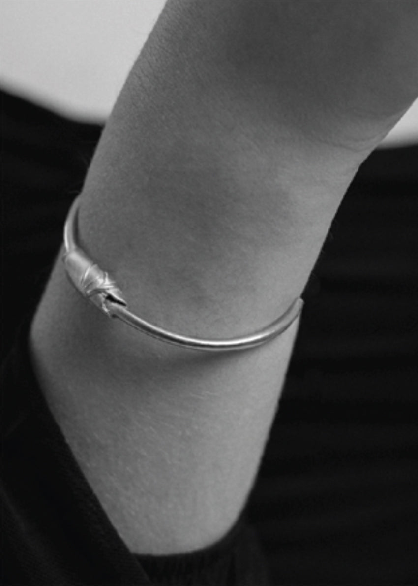 Silver bracelet on a wrist against a dark background