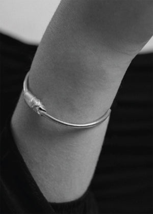 Silver bracelet on a wrist against a dark background