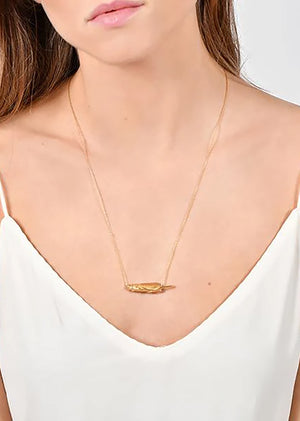 Gold necklace worn by a person against a white background
