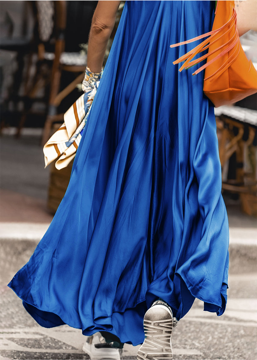 Woman wearing a blue silk dress with a orange bag