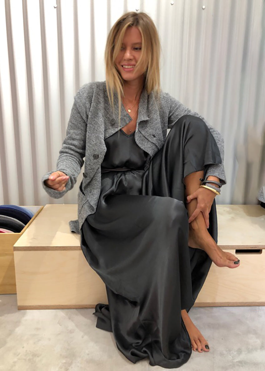 Woman wearing a dim grey silk dress with a grey cardigan 
