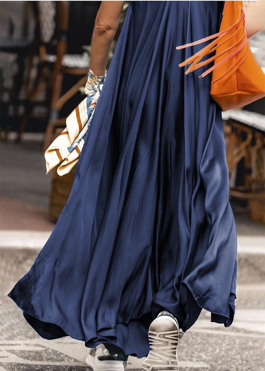 Woman wearing a silk midnight blue dress with a orange bag 